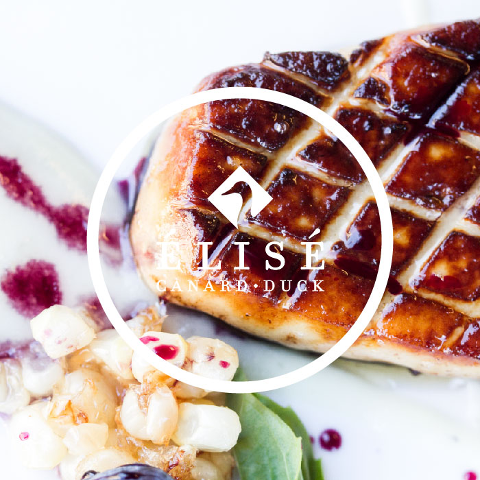 Elisé Canard/Duck logo superimposed over a white plate of cross-hatched seared foie gras with corn pudding and blueberries.